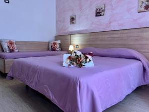 a bedroom with two beds with purple sheets and flowers at Le Essenze - Agriturismo con vista in Cesena +59 photos