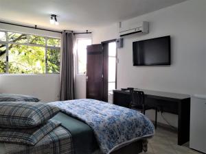 a bedroom with a bed and a desk and a television at Pousada Casa Verde - Curitiba in Curitiba
