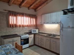 a kitchen with white appliances and a table in it at Colorina - El Nihuil in El Nihuil