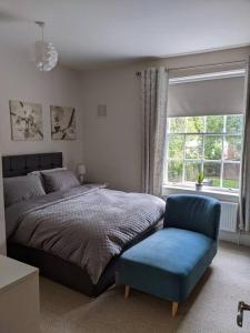 a bedroom with a bed and a blue chair at Beautiful Georgian townhouse in central Colchester in Colchester