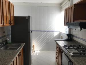 a kitchen with a black refrigerator and a sink at Apartamento Los Laureles Rodadero in Santa Marta