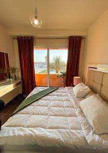 a bedroom with a large bed with a large window at Fully Equipped Apartments Pool & Mountains View in Porto Sharm Resort in Sharm El Sheikh