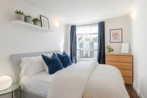 ein Schlafzimmer mit einem großen weißen Bett mit blauen Kissen in der Unterkunft The Dalston Maisonette in London