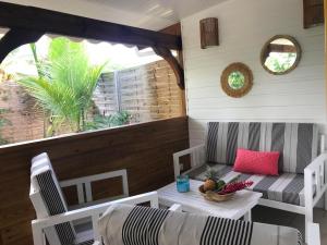 a porch with a couch and a table and chairs at Gites le petit voyageur in Sainte-Anne