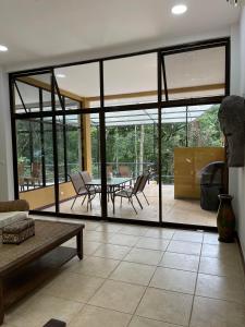 ein Wohnzimmer mit Glastüren, einem Tisch und Stühlen in der Unterkunft Private 5 Bedroom Home with Pool! in Tarcoles