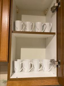 a cupboard filled with white coffee mugs on shelves at 3 bedroom home-inverkeithing in Fife