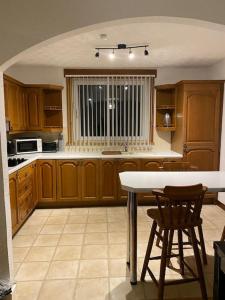 een keuken met houten kasten en een tafel en stoelen bij 3 bedroom home-inverkeithing in Fife