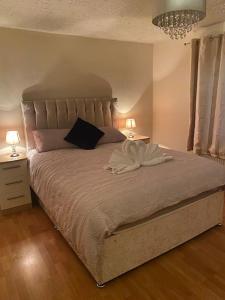 een slaapkamer met een groot bed met 2 nachtkastjes en 2 lampen bij 3 bedroom home-inverkeithing in Fife