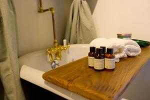 a bath tub with three bottles on a wooden tray at Archaic Outhouse in Santee +9 photos