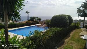 a swimming pool in a villa with palm trees at Residencial La Duquesa Suites Golf & Gardens in San Luis de Sabinillas