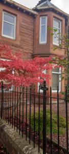 une clôture devant une maison avec un arbre rouge dans l'établissement Victorian apartment, central location with free parking., à Perth