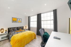 1 dormitorio con 1 cama con manta amarilla en Modern 2 bedroom apartment in the heart of London, en Londres
