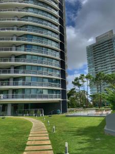 a large building with a grass field in front of it at Torre Tressesenta Apto 1508 in Punta del Este