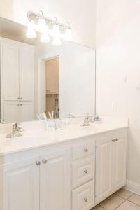 uma casa de banho branca com 2 lavatórios e um espelho grande em Spacious King Suite Mid Town Home With Serene Patio em Hattiesburg