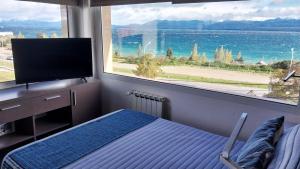 a bedroom with a large window with a view of the ocean at Las Victorias Suites Bariloche in San Carlos de Bariloche