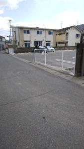 eine leere Straße mit einem Zaun und einem Parkplatz in der Unterkunft Ikkenya Tsushima in Okayama