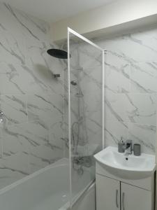 a white bathroom with a shower and a sink at London's Calling U! A Lovely 2 BedHome Sleeps 1-5! in London
