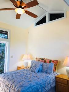 a bedroom with a blue bed with a ceiling fan at Holualoa bungalow 1 in Kailua-Kona