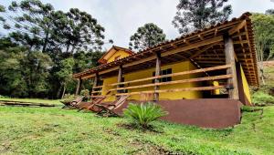 a small yellow house with chairs in a field at A CASA AMALELA in Gonçalves