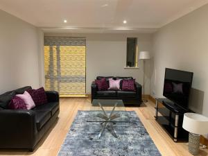 uma sala de estar com dois sofás pretos e uma televisão em Killarney Town Apartment em Killarney
