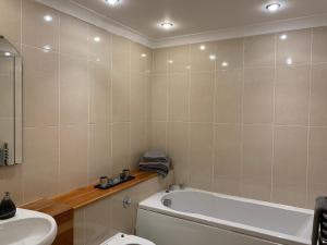 a bathroom with a tub and a toilet and a sink at Killarney Town Apartment in Killarney