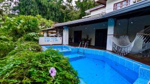 a swimming pool with a hammock next to a house at Nova Beautiful boutique hotel Manuel Antonio in Manuel Antonio