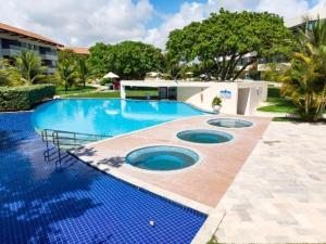 una gran piscina con azulejos azules alrededor. en Carneiros Beach Resort - Apto 214D, en Tamandaré