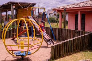 a young boy sitting on a swing at a playground at Pousada Chalés Beach - Praia do Rosa in Praia do Rosa