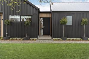 a black house with two trees in front of it at Luxe Arrowtown Home in Arrowtown