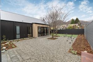 a house with a gravel driveway next to a building at Luxe Arrowtown Home in Arrowtown