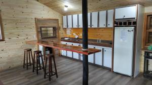 a kitchen with a large wooden counter and stools at CASA TEMPORADA SANTO ANTONIO in Urubici