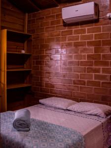 a bedroom with a brick wall with a bed and aperature at Pousada Chalés Beach - Praia do Rosa in Praia do Rosa