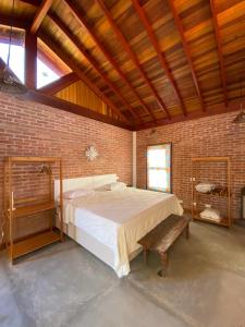 a bedroom with a large bed in a brick wall at Casa Serrinha - Lindo e Espaçoso Chalé in Bueno Brandão