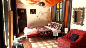 1 dormitorio con 1 cama y 1 silla roja en Quirky Woods - Glamping Cabins at Maketu, en Maketu