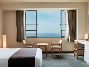 a hotel room with a bed and a desk and a window at KAMENOI HOTEL Awajishima in Awaji