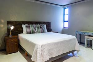 1 dormitorio con cama blanca y ventana en Lotus Midtown Apartments by BVR, en Playa del Carmen