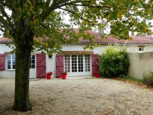 ein weißes Haus mit roten Türen und einem Baum in der Unterkunft Gîte Charroux - Allier, 4 pièces, 7 personnes - FR-1-489-271 in Charroux-dʼAllier