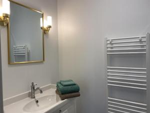 a white bathroom with a sink and a mirror at Appartement Équipé au Cœur de Vichy – Confort et Praticité - FR-1-489-366 in Vichy +9 photos