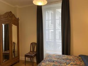 a bedroom with a window and a bed and a mirror at Appartement Équipé avec Balcon au Cœur de Vichy - Proche Thermes et Commerces - FR-1-489-362 in Vichy