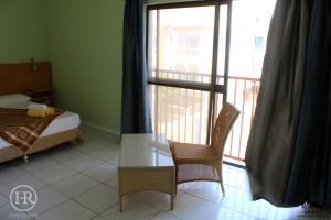 a room with a bed and a table and a balcony at Hotel Roterdão "Under New Management" in Praia