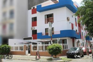 a white and red building with cars parked in front of it at Hotel Roterdão "Under New Management" in Praia
