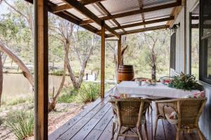 a table on a screened porch with a view of a river at Long Alley Barn in Hartley Vale