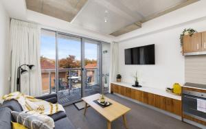 a living room with a couch and a large window at Mode Apartments Braddon ACT in Canberra