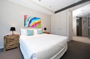 1 dormitorio con 1 cama blanca grande y ducha en Aurora 14, en Canberra
