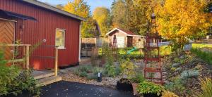 a garden next to a red building with a garden ladder at Bålsta Studio Houses in Bålsta