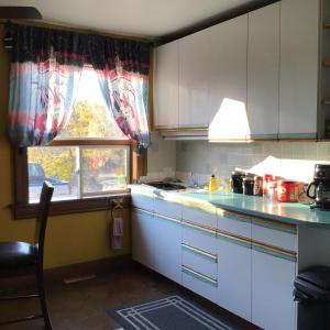 une cuisine avec des placards blancs et une fenêtre dans l'établissement Nisku Guest House, à Nisku