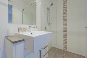 a white bathroom with a sink and a shower at Domain 8 Deakin ACT in Canberra