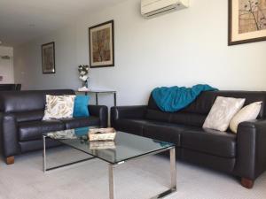 a living room with a black leather couch and a table at Aspire 45 in Canberra