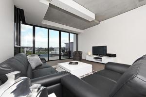 sala de estar con muebles de cuero negro y TV en The ApARTments 403 Canberra City ACT, en Canberra