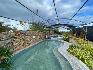 a swimming pool with a stone wall and an umbrella at LaSersita Casitas and Water Spa Beach Resort by Cocotel 